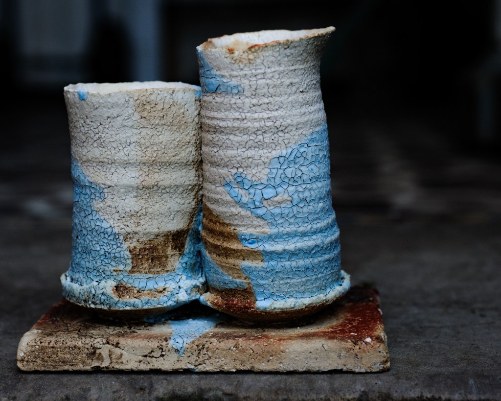 Zwei keramische Gefäße mit rissiger weiß-blauer Glasur auf einem Unterteller.